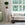 Cream sofa with decorative pillows in a room with large windows and a plant on a pedestal.