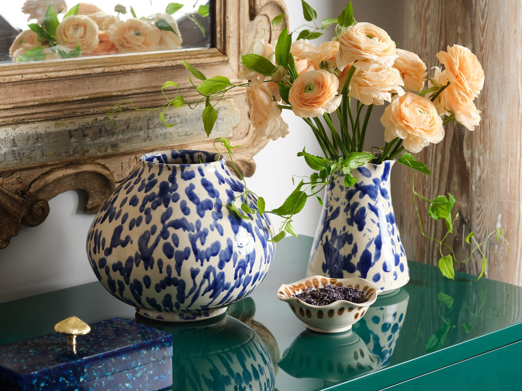 two ceramic vases on top of a green georgia chest by bunny williams home