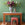 Decorative table with a large flower arrangement and a small statue against a green patterned wall.