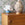 Decorative items on a wooden dresser with floral arrangement and patterned wallpaper.