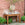Wooden outdoor table with marble top against a brick wall, surrounded by potted plants.