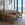 Bedroom with wooden poster bed and wicker bench by large windows with ocean view