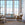 Living room with large windows, beige sofa, and wicker chair.