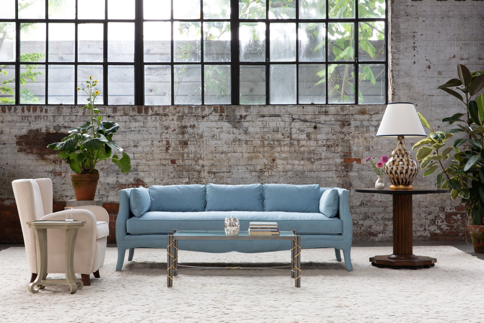 light blue upholstery couch against brick wall and window