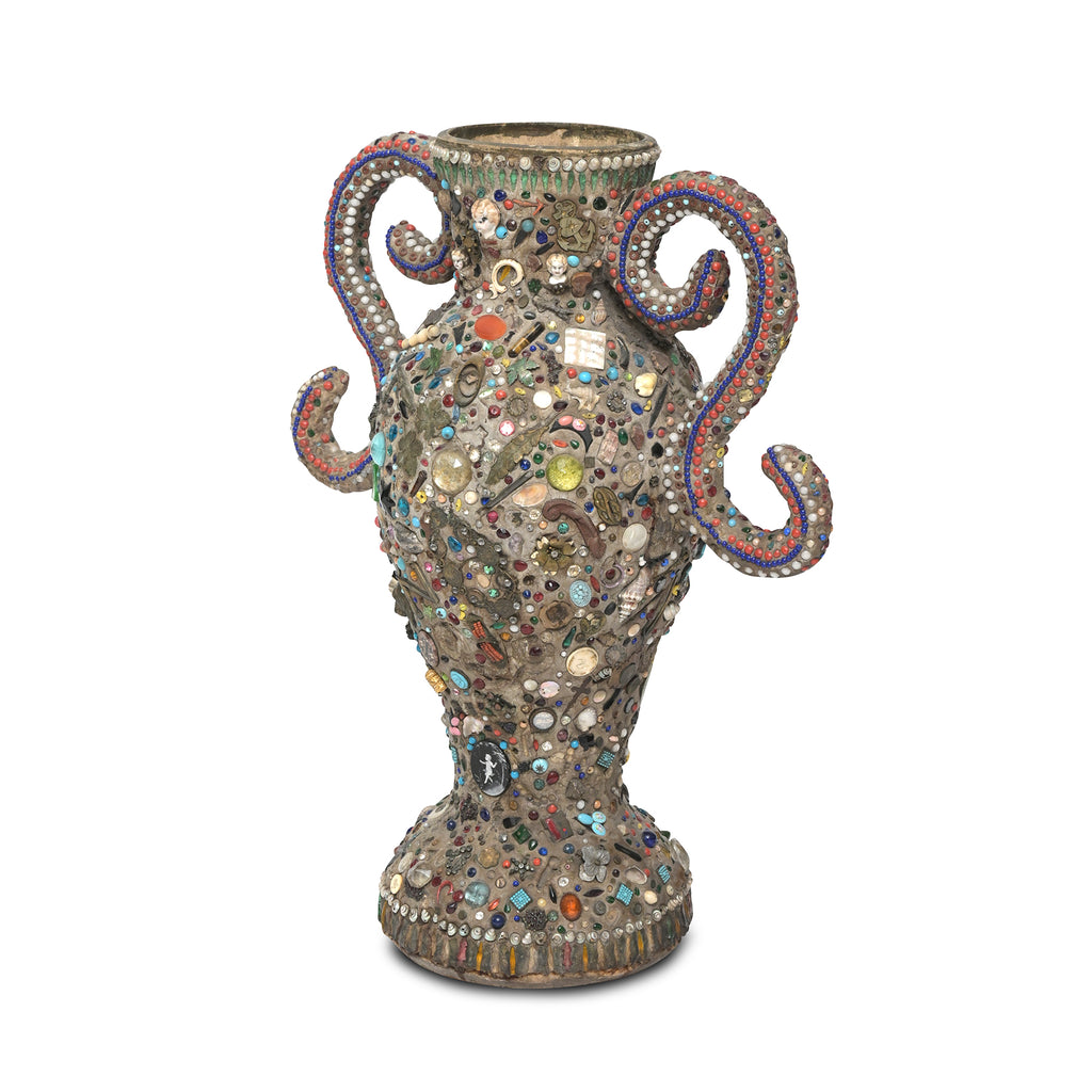 a diagonal side view of a folk art memory vase folk art memory vases, with a surface showcasing various mementos