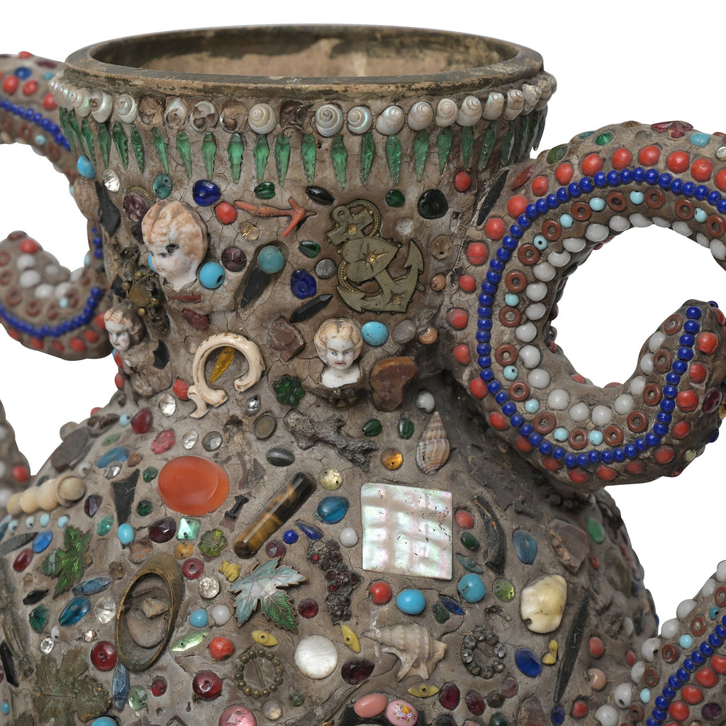 a close up view of the various mementos, shells, and beads embedded in the memory vase's surface