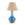 A ceramic table lamp with a blue ombre glaze and cream undertones, perched atop a gold base, with a beige lampshade.
